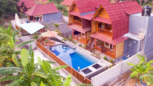 A resort with multiple bungalow-style buildings, a swimming pool, and lush tropical vegetation. - Putra Bali Villa (Penida Island)