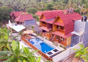 A resort with multiple bungalow-style buildings, a swimming pool, and lush tropical vegetation. - Putra Bali Villa (Penida Island)