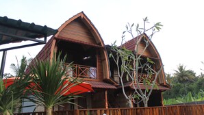 A wooden house with a balcony and a red umbrella. - Putra Bali Villa (Penida Island)
