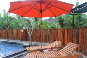 Una piscina al aire libre, sillones reclinables de piscina