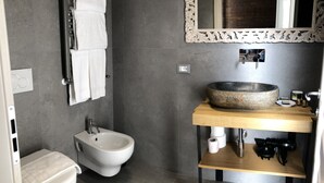 A modern bathroom with a bidet, a large mirror, and a stone sink. - Chalet Lucca (Lucca)