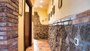 A hallway with a brick wall on one side and a stone wall on the other, leading to a door. - B&B Casale Ansamagi Relax & Pool (Genzano di Roma)