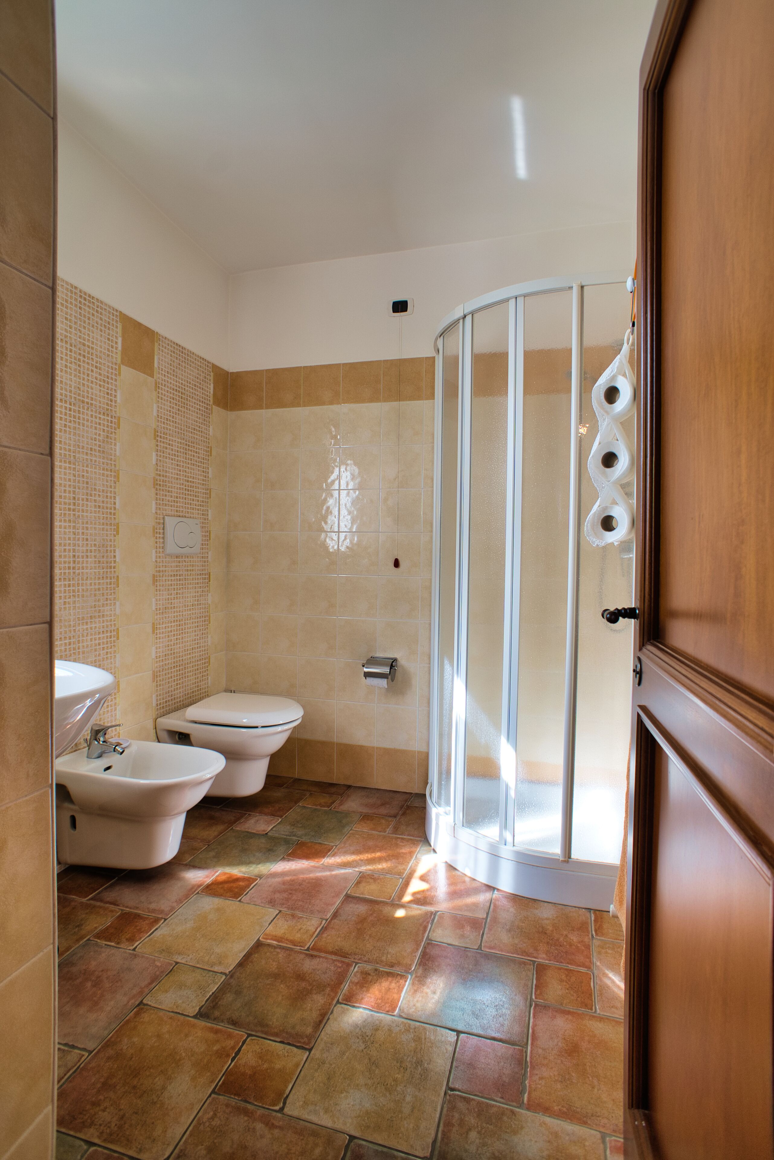 Un baño con ducha, dos lavamanos y un inodoro.