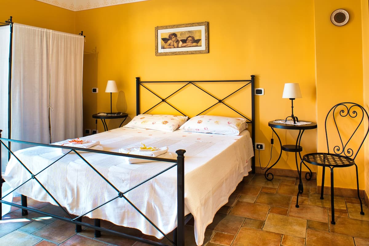 A bedroom with a bed, two bedside tables, a chair, and a ceiling light fixture.