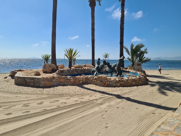 A beach with palm trees, a statue of a man on a horse, and a clear blue sky. - Three Double Bedroom Townhouse in Lovely Village (San Javier)