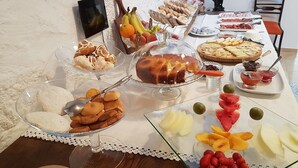 Buffet amb diverses opcions gastronòmiques, com fruita, pastissos i un pastís.