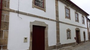 Un edifici històric amb façana blanca, base de pedra i nombroses portes i finestres.