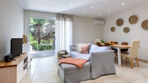 Una sala de estar moderna con sofá, televisión y comedor.