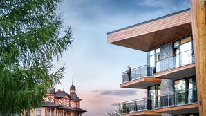 Un edificio moderno con un balcón y un edificio tradicional al fondo.