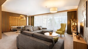 Una sala de estar moderna con un sofá seccional, una mesa de centro redonda, un sillón de respaldo alto y una zona de comedor con una mesa y sillas blancas.