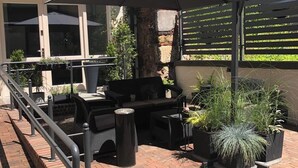 An outdoor patio with a dining set, a large umbrella, and potted plants. - Ermine Suites (Kraków)