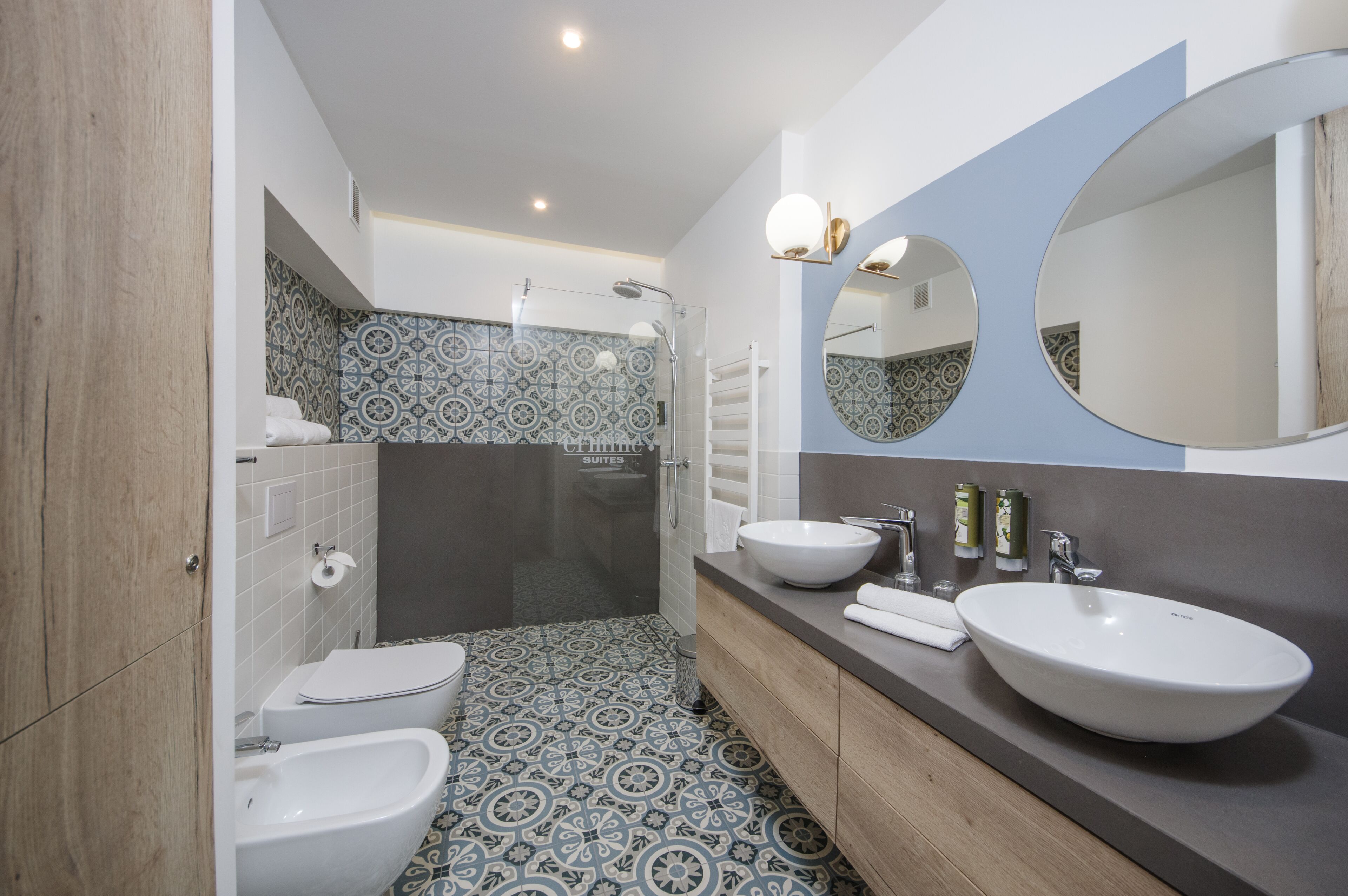 A modern bathroom with a bidet, a toilet, a large sink, and a shower area.