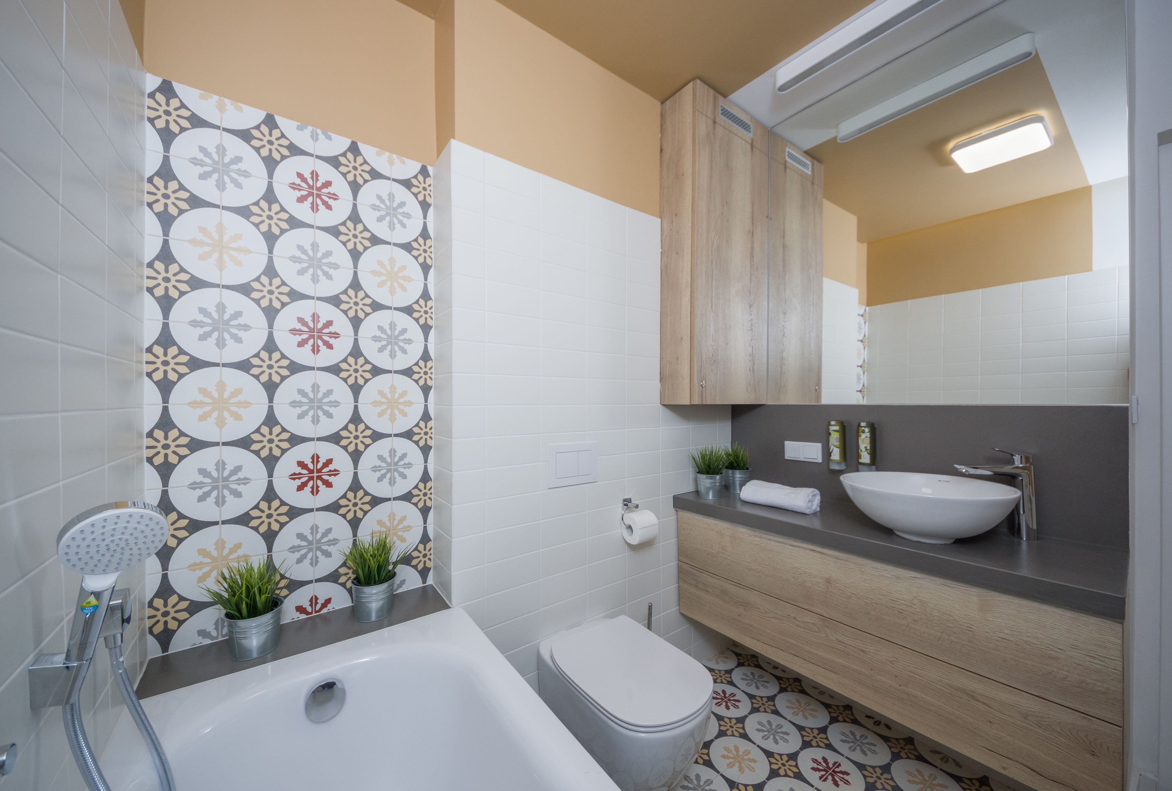 Une salle de bain moderne équipée d’une baignoire, de toilettes, d’un lavabo et d’un miroir au-dessus du meuble-lavabo.