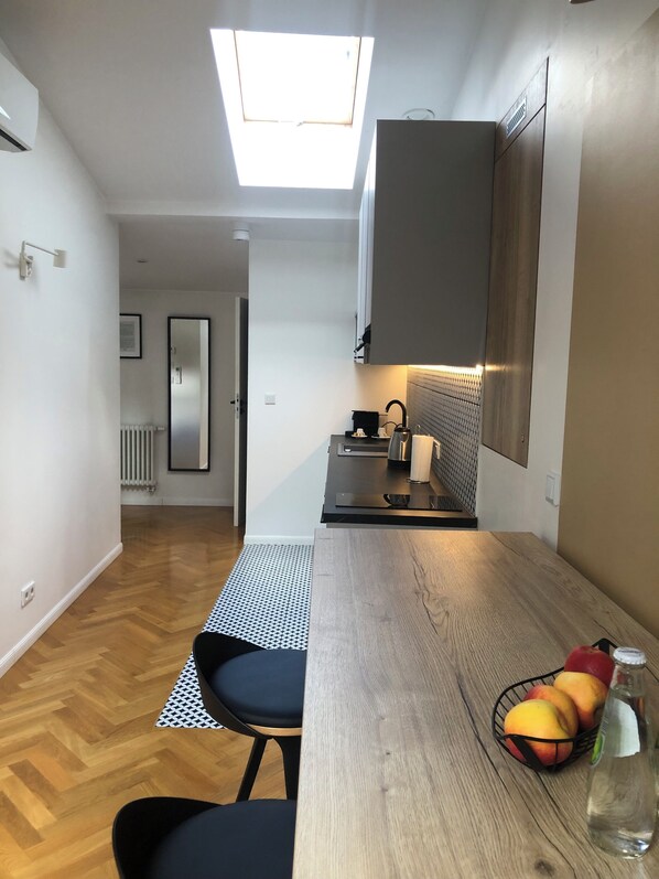 Una cocina moderna con tragaluz, suelo de madera y comedor con mesa y sillas.