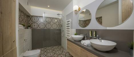 A modern bathroom with a patterned floor, a large sink, and two mirrors.