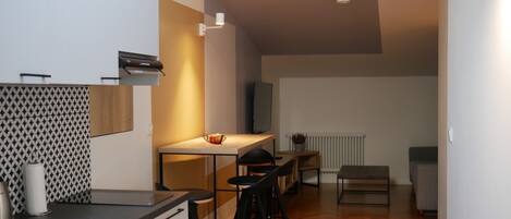 A modern kitchen with a dining area, wooden flooring, and a radiator.