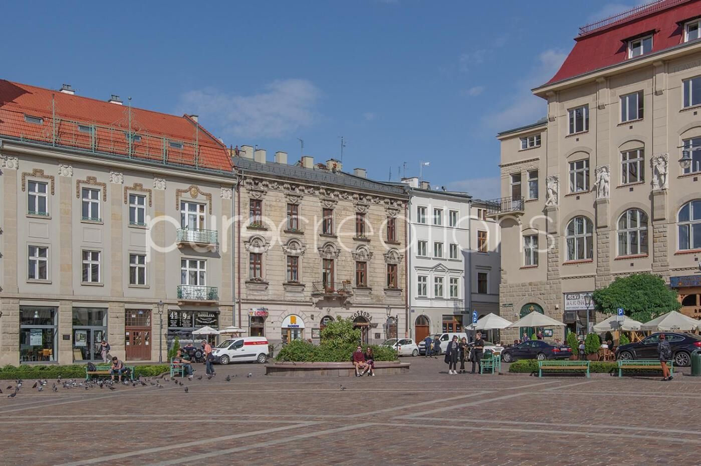 Een openbaar plein met historische gebouwen, banken en een centrale fontein.