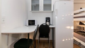 A compact kitchenette with a microwave, coffee maker, and white cabinets. - Skyhostel Friedrichshafen (Friedrichshafen)