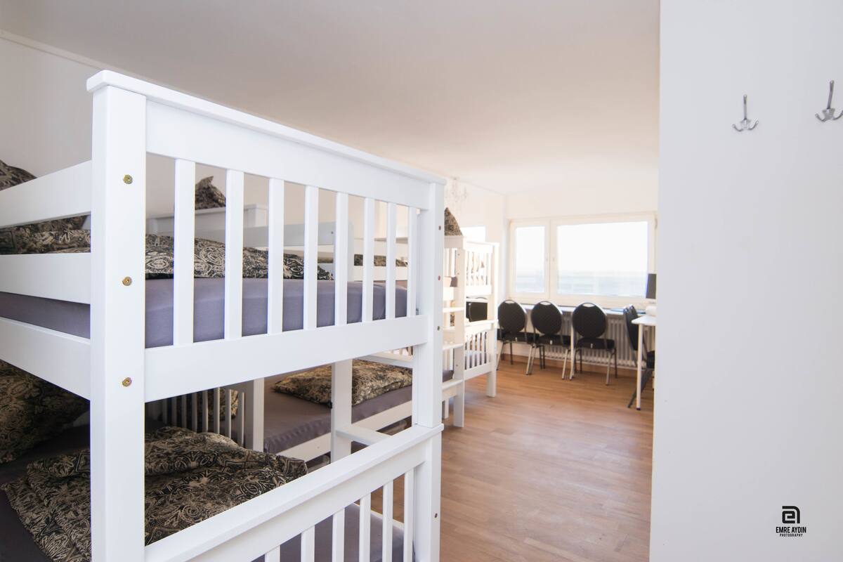 A room with bunk beds, a desk, chairs, and a view of the sea.