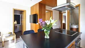 A modern kitchen with a black countertop, a built-in stove, and a vase of flowers on the table.