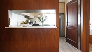 A kitchen with a wooden island, a bowl of fruit, and a vase of flowers.
