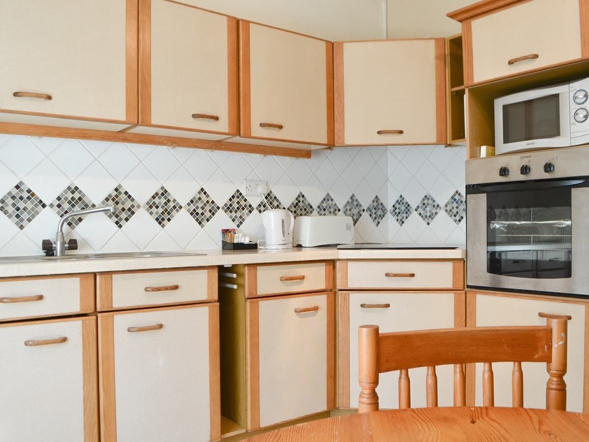 A kitchen with wooden cabinets, a microwave, an oven, and a tiled backsplash.