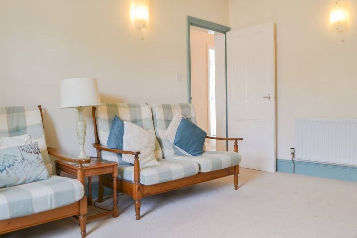 A room with a sofa set, two lamps, and a radiator.