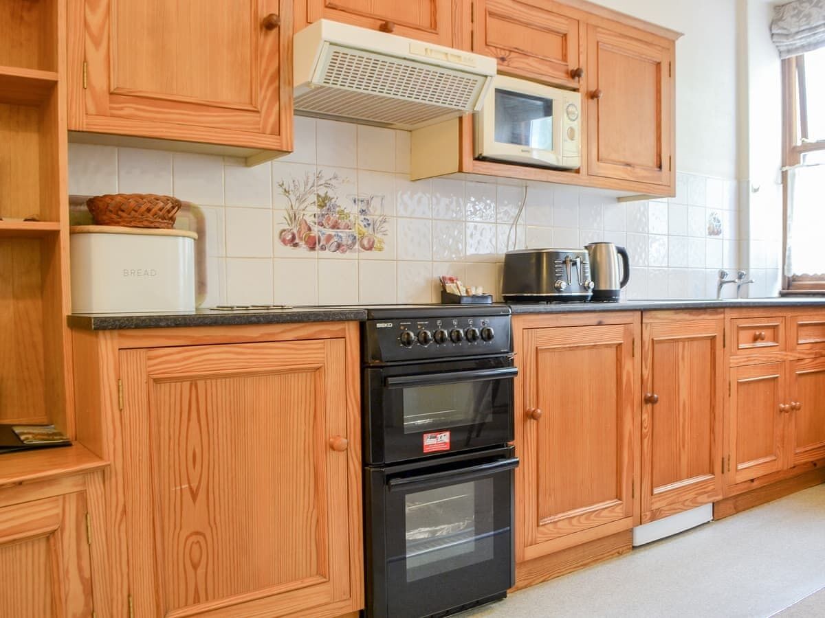A kitchen with wooden cabinets, a microwave, a stove, and a toaster.
