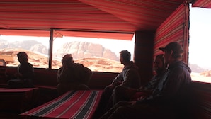 A group of people seated inside a vehicle with a view of rocky desert landscape. - Bedouin Nomads Adventures (Wadi Rum)