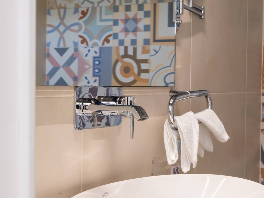 Een badkamer met een witte wastafel, een spiegel en een handdoekhouder.