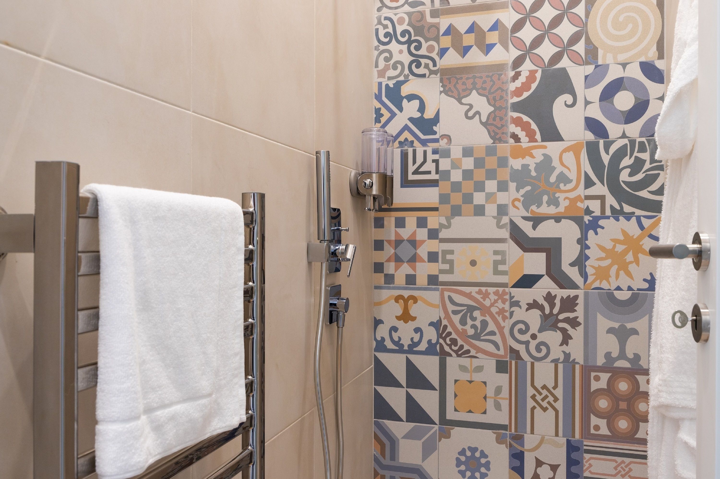 Un baño con toallero, ducha y azulejos decorativos.