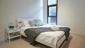 A modern bedroom with a bed, a bedside table with a lamp, and a window with a view of the outside. - Walk To Darling Harbour 1 BED NEW APT Nsy188 (Sydney)
