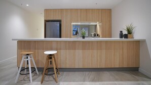A modern kitchen with a wooden countertop, two stools, a refrigerator, and a sink. - Walk To Darling Harbour 1 BED NEW APT Nsy188 (Sydney)