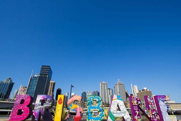 Un horizonte urbano con edificios altos y la palabra "BRISBANE" escrita con letras de colores.