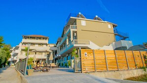 A multi-story hotel with balconies, outdoor seating, and a gated entrance. - Hotel Emilia (Zakynthos)