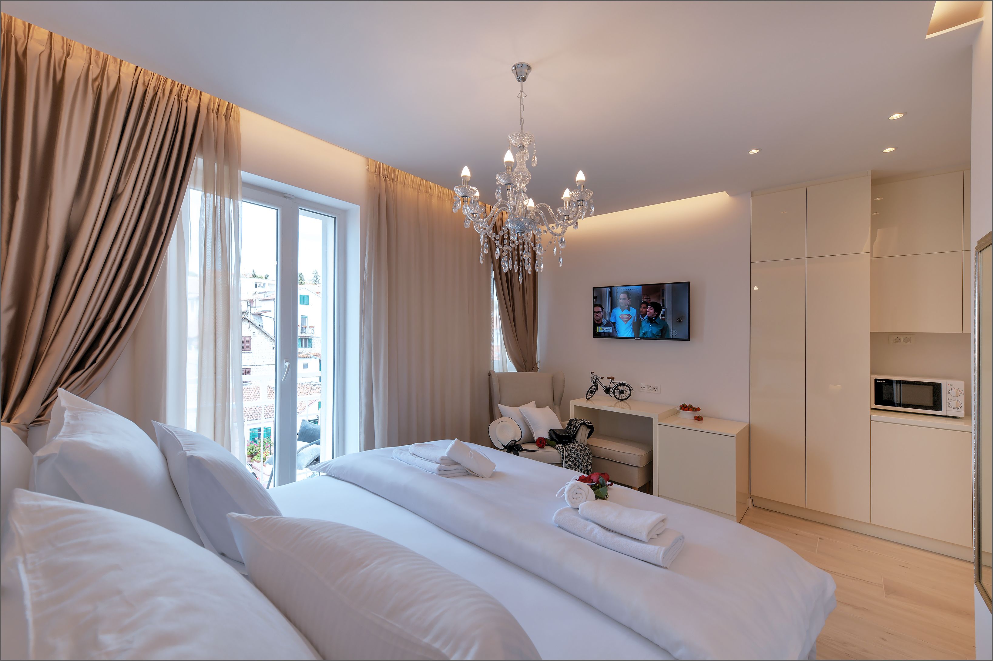 Une chambre d’hôtel moderne dotée d’un grand lit, d’une télévision, d’un minibar et offrant une vue sur la ville.