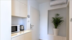A small kitchenette with a microwave, coffee maker, and white cabinets.
