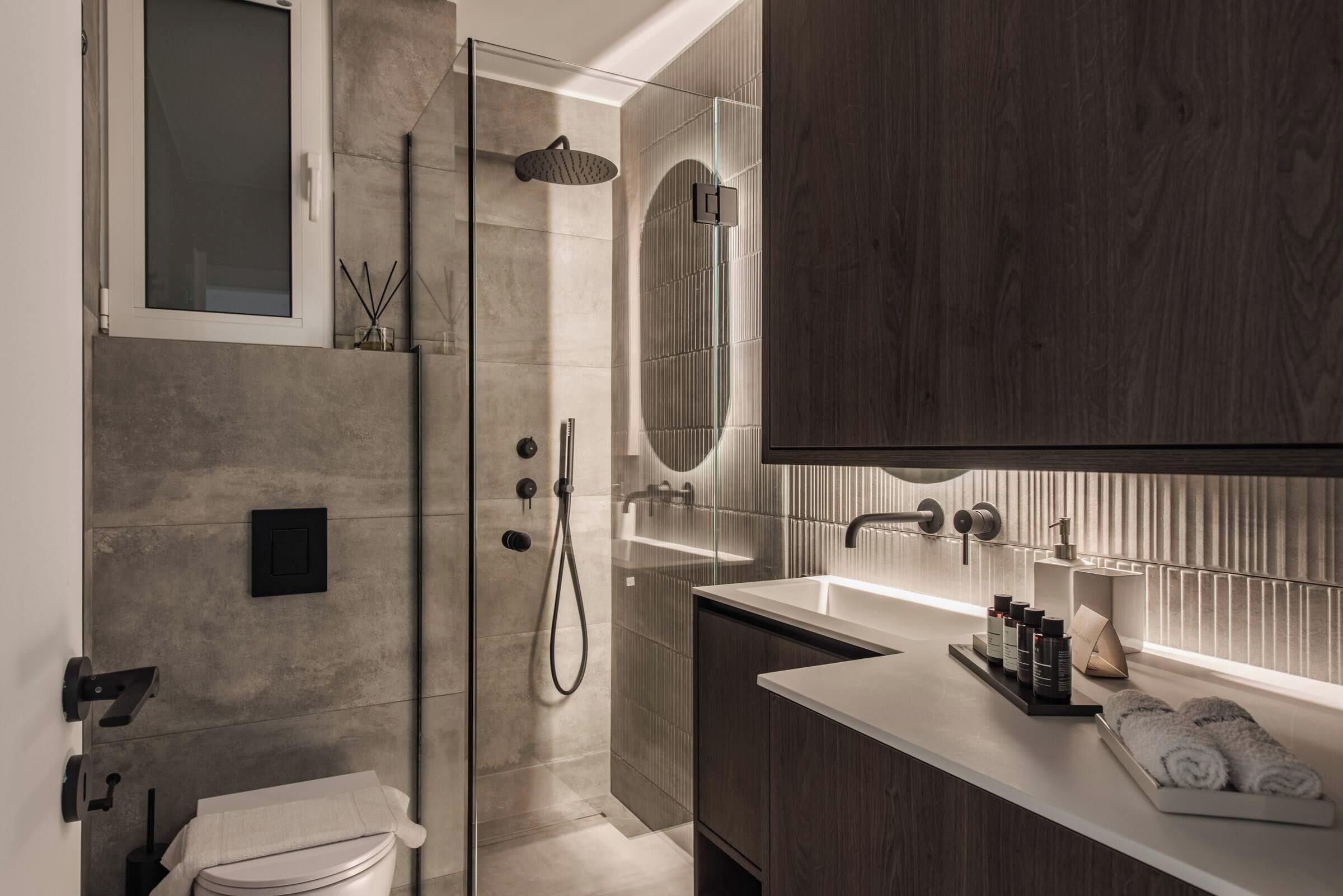 Un bagno moderno con cabina doccia in vetro, lavabo bianco e mobile bagno in legno.