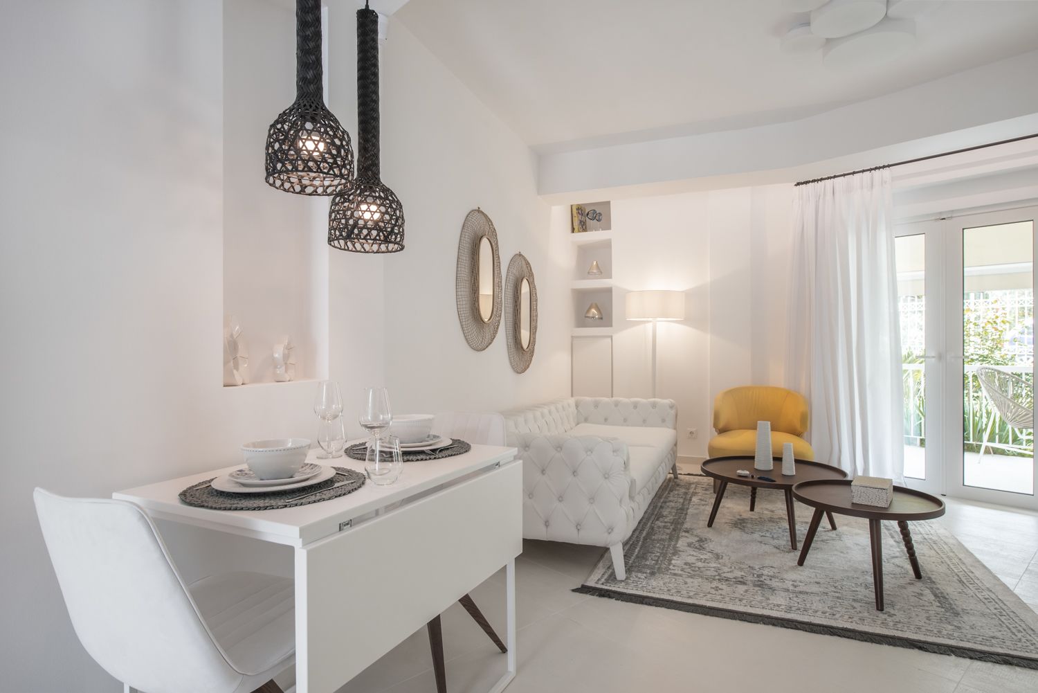 Un comedor moderno con una mesa blanca para cuatro, un sofá capitonado, un sillón amarillo y una alfombra estampada.
