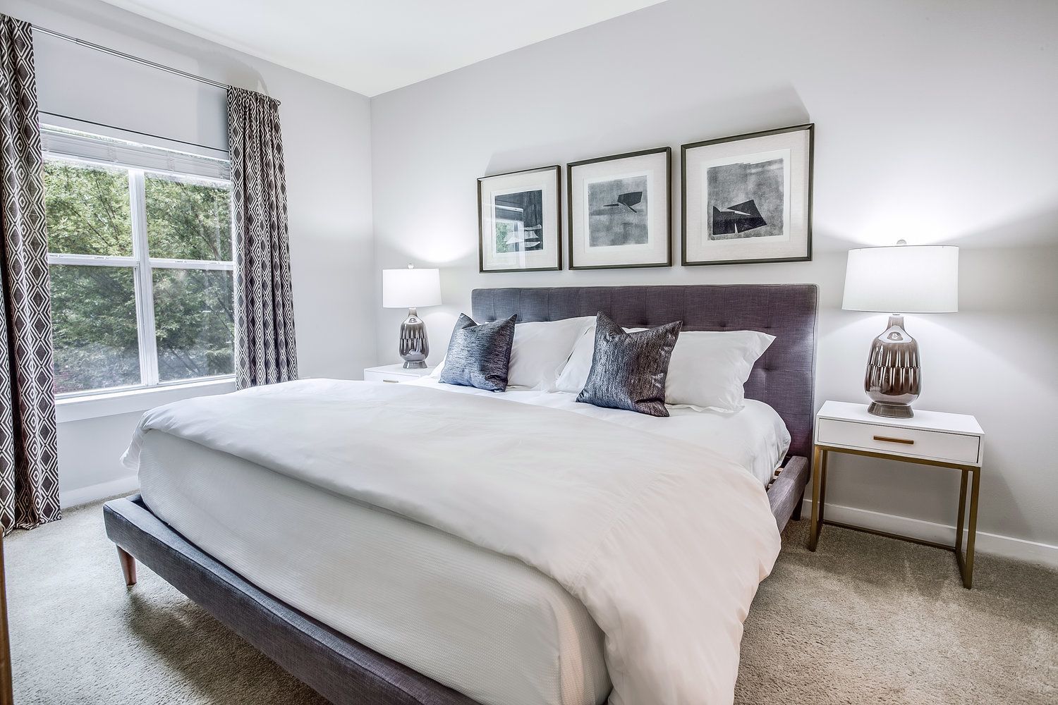 A bedroom with a large bed, two bedside tables, and a window with curtains.