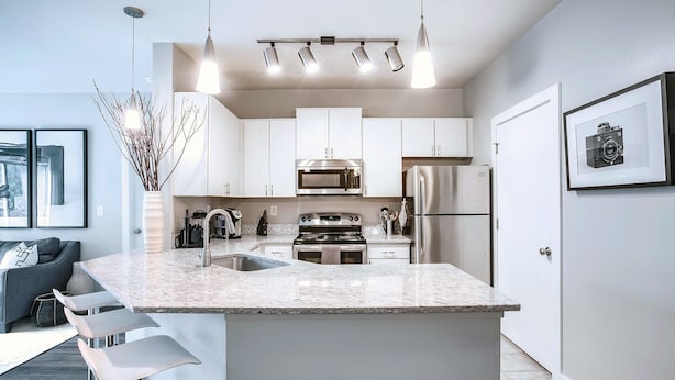 A modern kitchen with white cabinets, stainless steel appliances, and a granite countertop. - Picture Perfect (Atlanta)