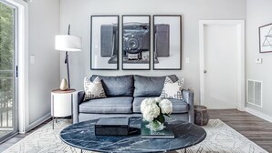A modern living room with a grey sofa, a round coffee table, and framed artwork on the wall. - Picture Perfect (Atlanta)