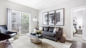 A modern living room with a sofa, a coffee table, and a chair. There is a large window with a view of the outdoors. - Picture Perfect (Atlanta)