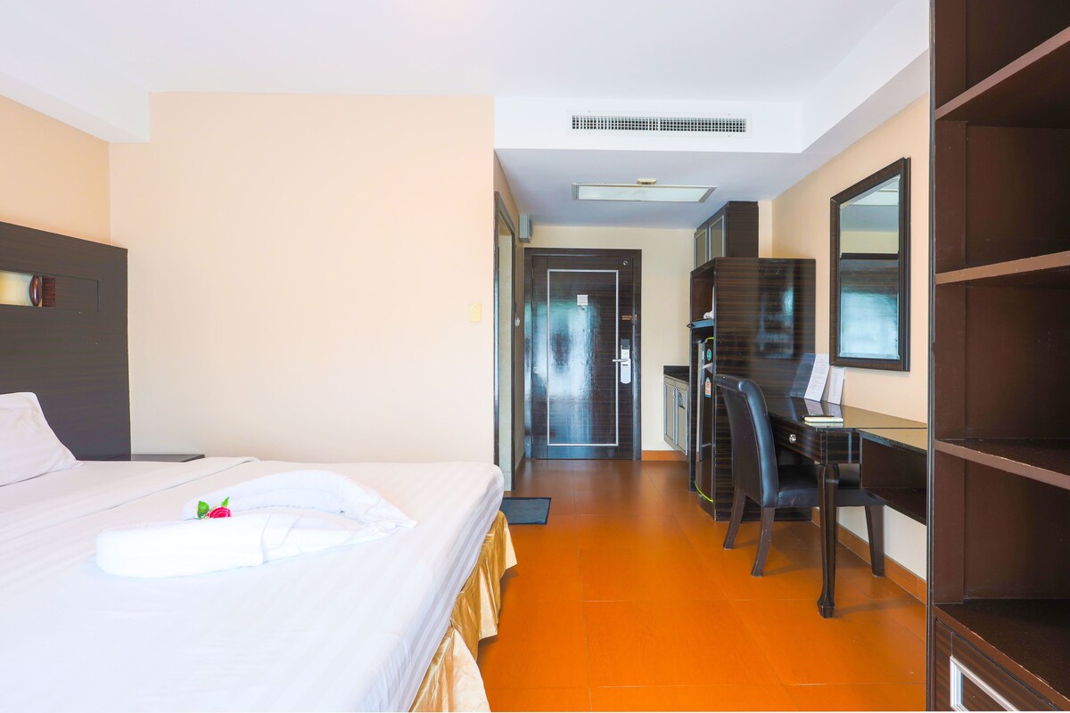 A hotel room with a bed, desk, and wardrobe.