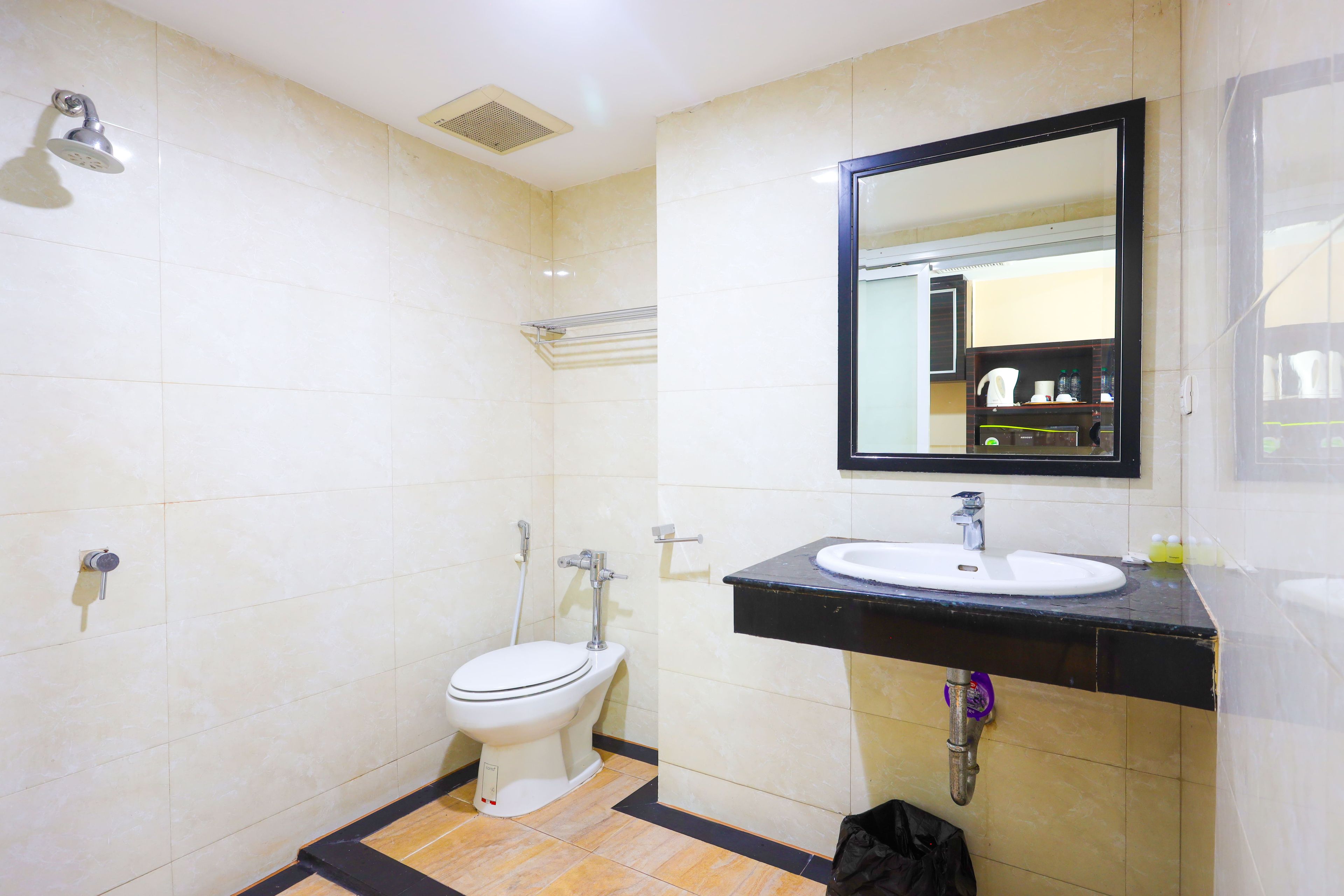 A bathroom with a toilet, a sink, a shower, and a mirror.