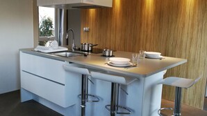 Una cocina moderna con una isla central, taburetes de bar y vistas al exterior.