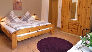 A bedroom with a wooden bed, a purple rug, a wooden wardrobe, and a mirror.