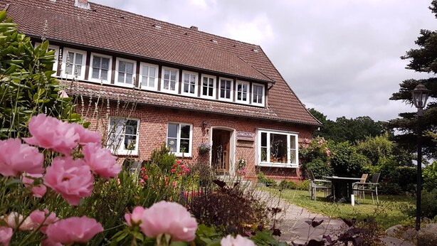 A two-story brick house with a garden in front.