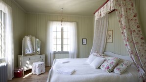 A bedroom with a canopy bed, a dresser, a mirror, and a window with curtains. - STF Sala Silvergruva (Sala)