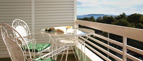 A balcony with a table and chairs, a book, and a glass of water.